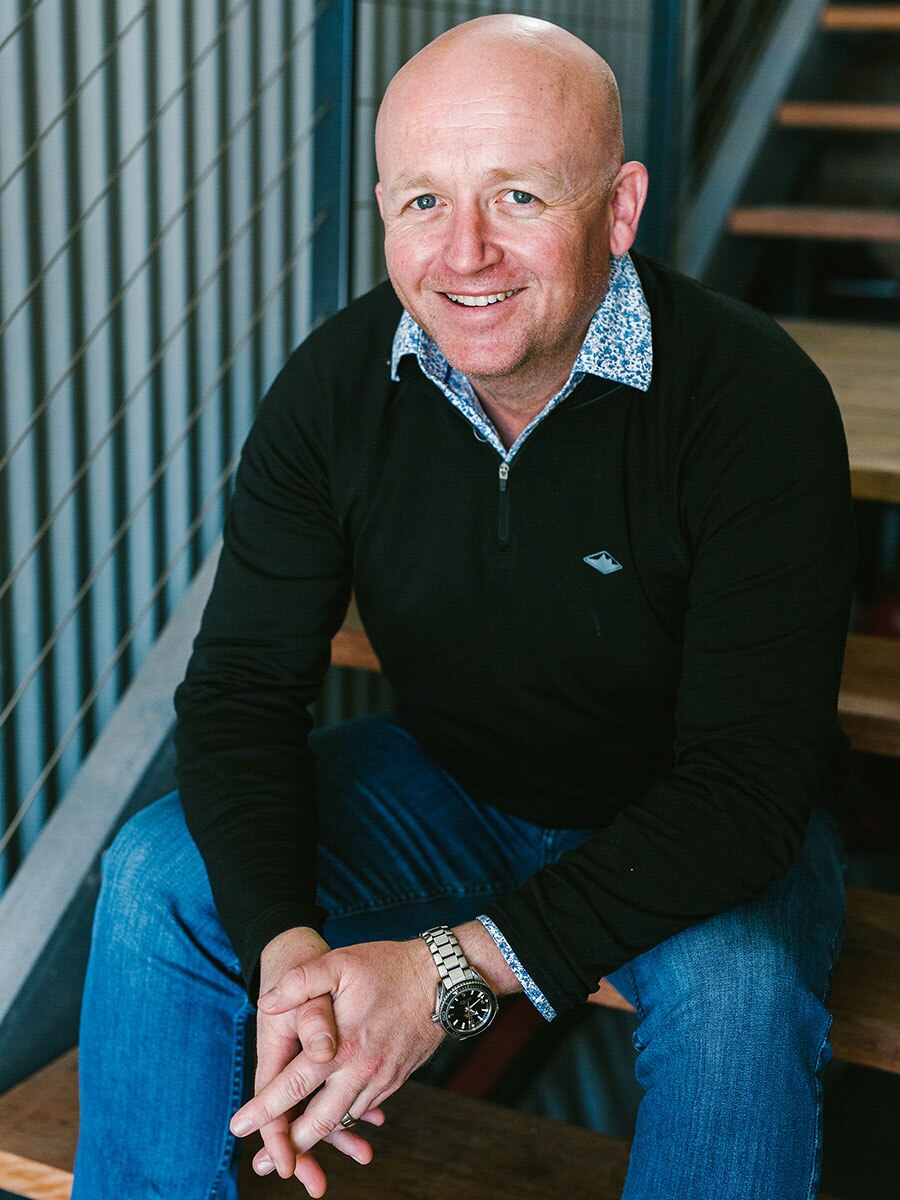 Landscape architect David Moir sits on a step and smiles at the camera