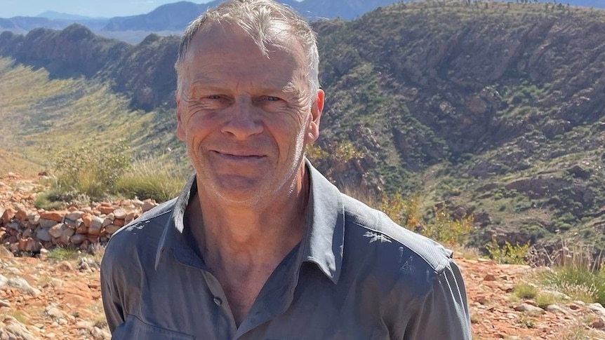 Alistair Thomson stands in front of the West MacDonnell Ranges.