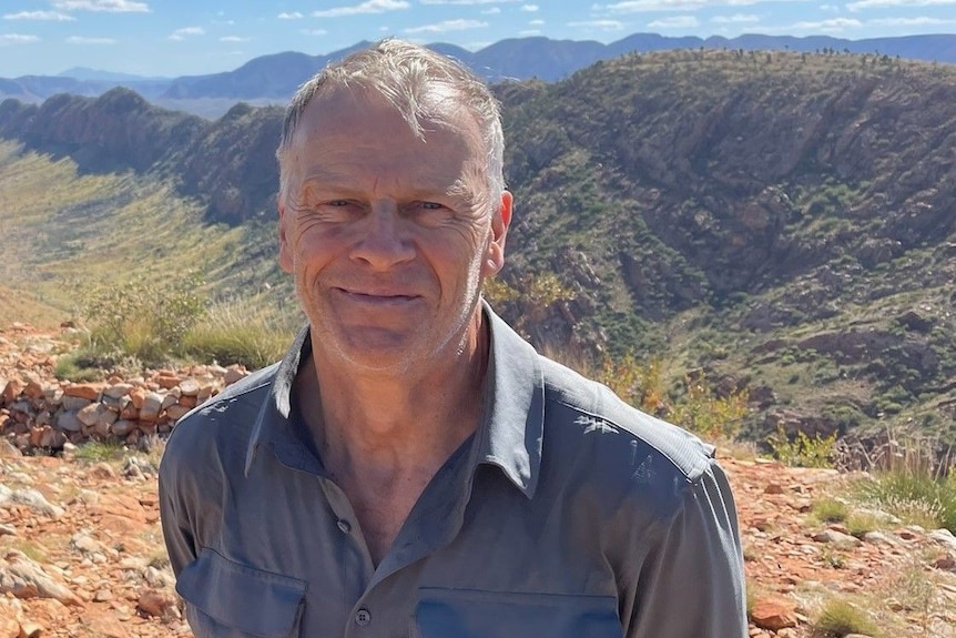 Alistair Thomson stands in front of the West MacDonnell Ranges.