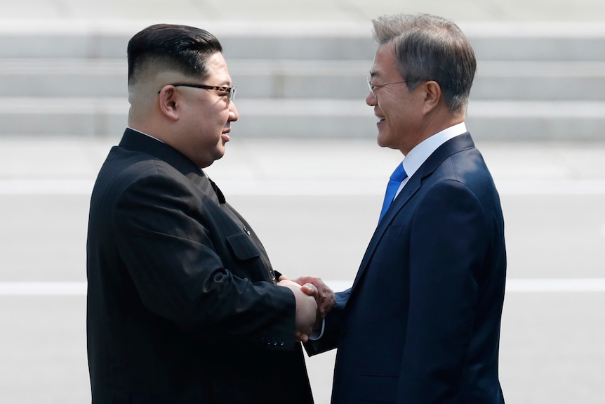 Kim Jong-un shakes hands with Moon Jae-in.
