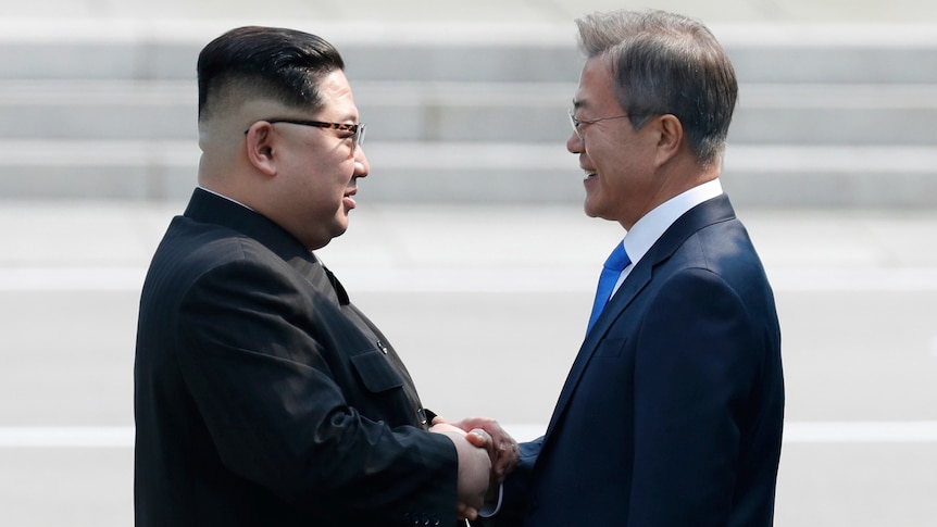 Kim Jong-un shakes hands with Moon Jae-in.