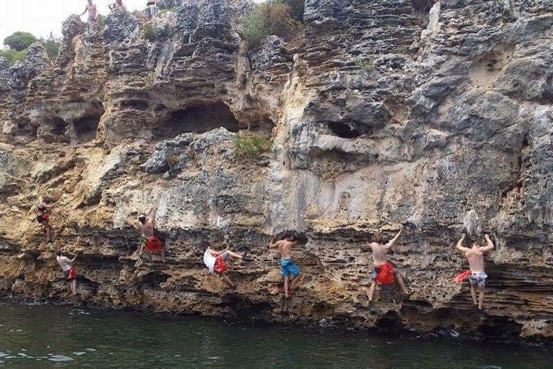 Seven climbers traverse a cliff above the river.