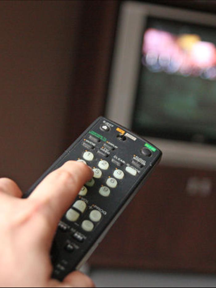 hand points a remote at a television