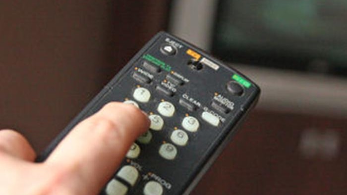 hand points a remote at a television