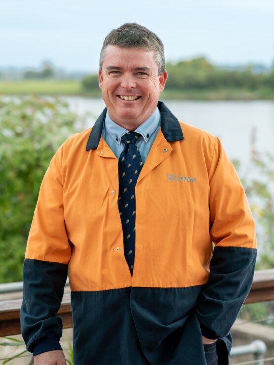 Man in tie and bright orange jacket smiling. 