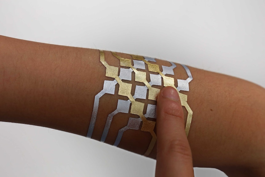 A metallic, pattern tattoo on a person's arm.