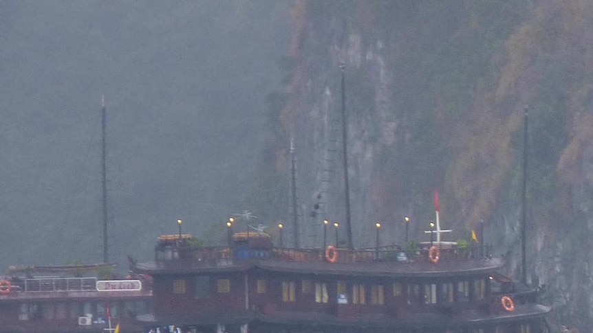 A police boat sits next to the submerged tourist boat that sunk in Halong Bay