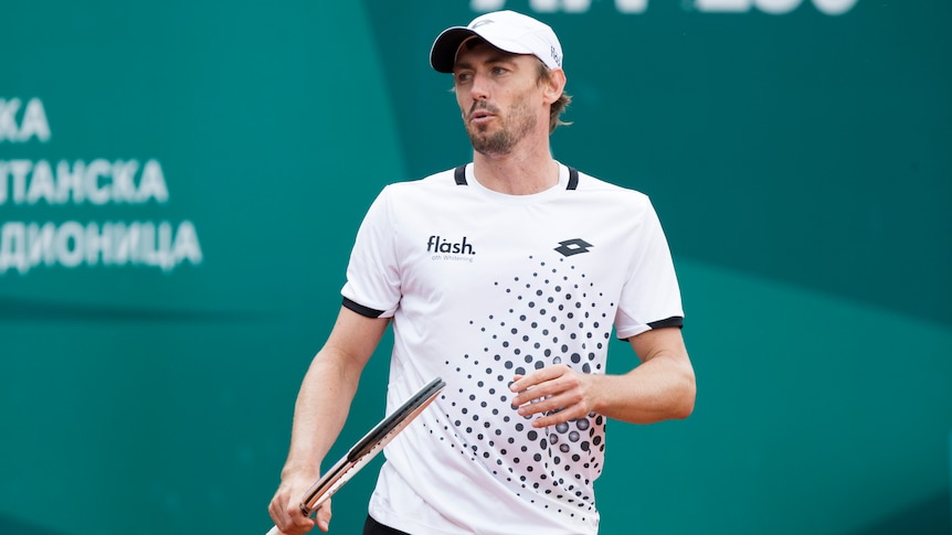 John Millman blows air out of his mouth through pursed lips and looks off to his right