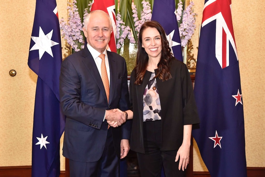 Prime Minister Malcolm Turnbull shakes hands with New Zealand counterpart Jacinda Ardern in front of flags and flowers