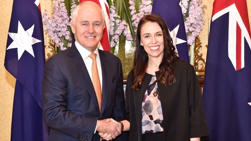 Prime Minister Malcolm Turnbull shakes hands with New Zealand counterpart Jacinda Ardern in front of flags and flowers