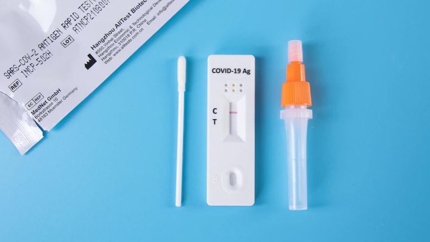 Rapid antigen testing kit laid out on a blue background.