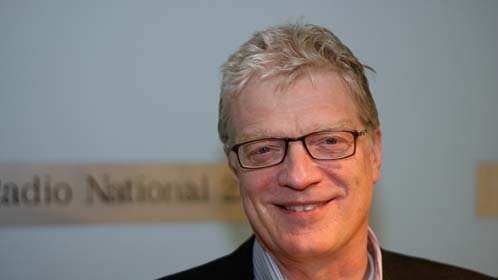 a head shot of a smiling fair haired man wearing glasses