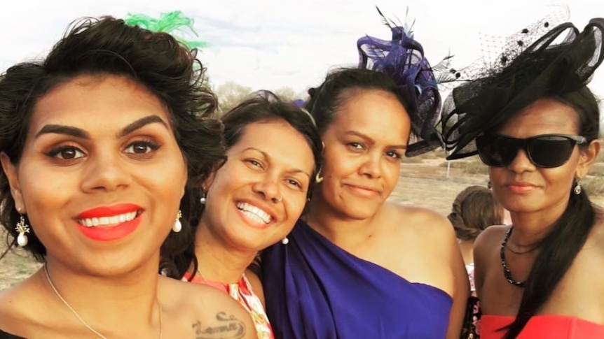 Four women in formal dresses posing for a photo.