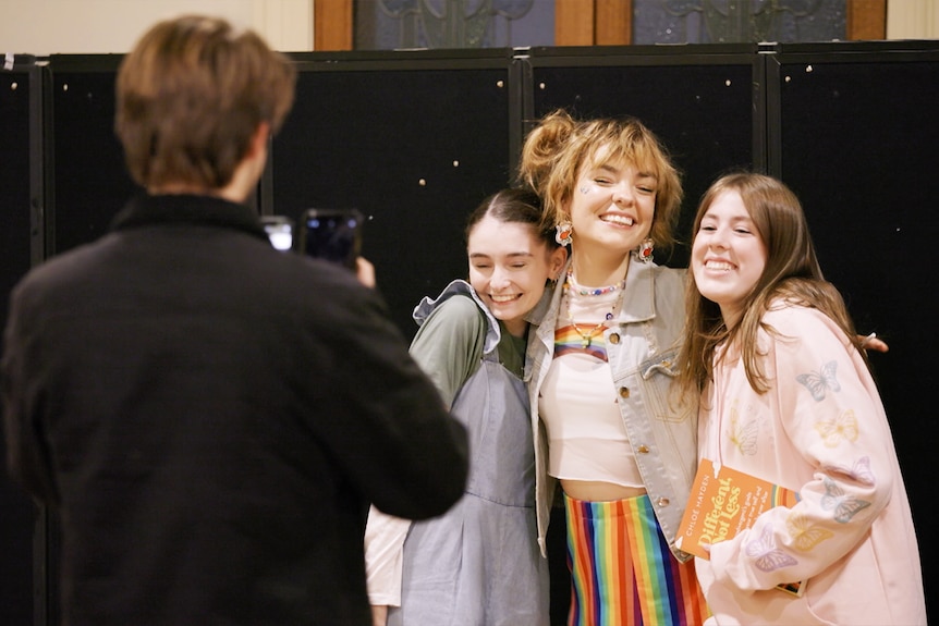 Chloé takes a picture with two young girls. 