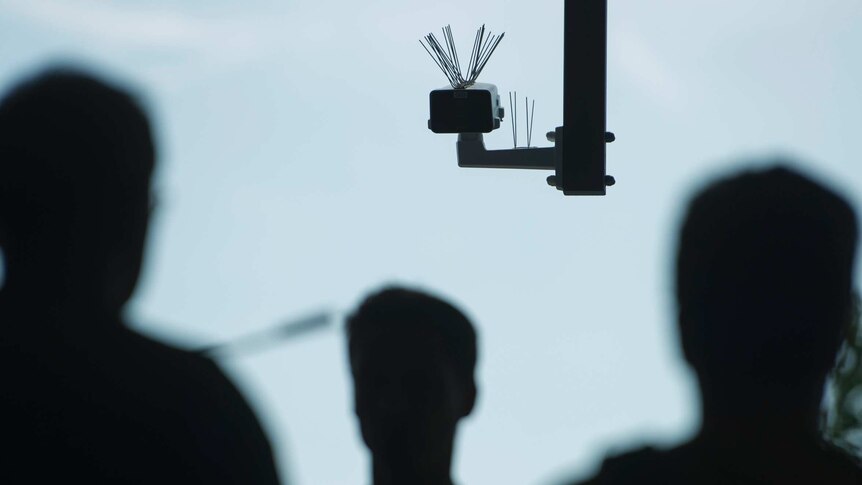 Passersby walk under a surveillance camera that is part of a facial recognition technology test in a train station in Berlin.