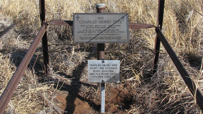 A grave marker on a post with fence.