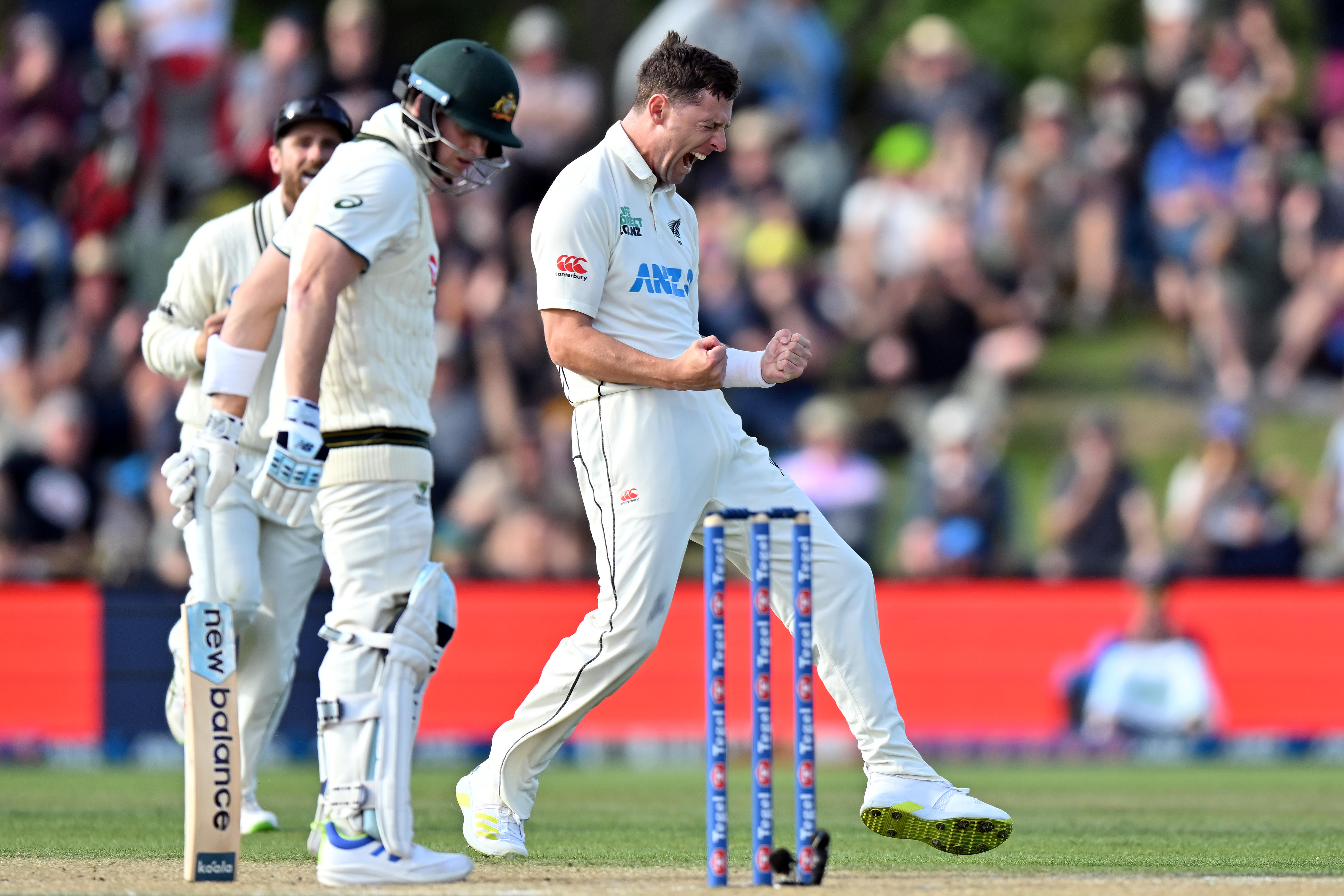 Matt Henry pumps his fists and yells in delight as Steve Smith looks disappointed