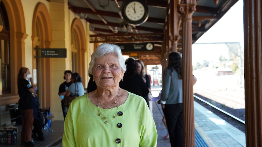 A woman in a green shirt standing on a train platform