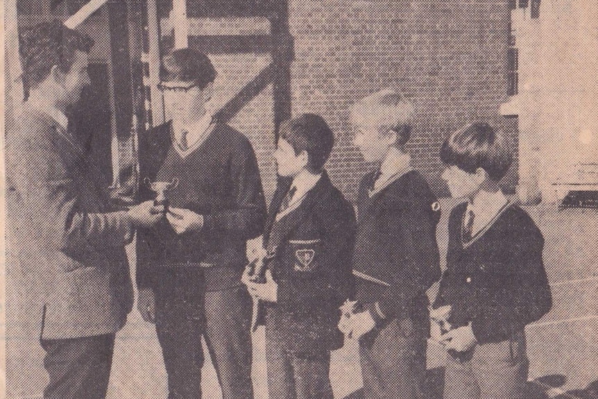 A newspaper clipping shows four boys receiving trophies.