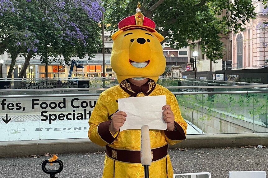 A protester dressed in a IWinne the pooh costine holding up a blank piece of paper. 