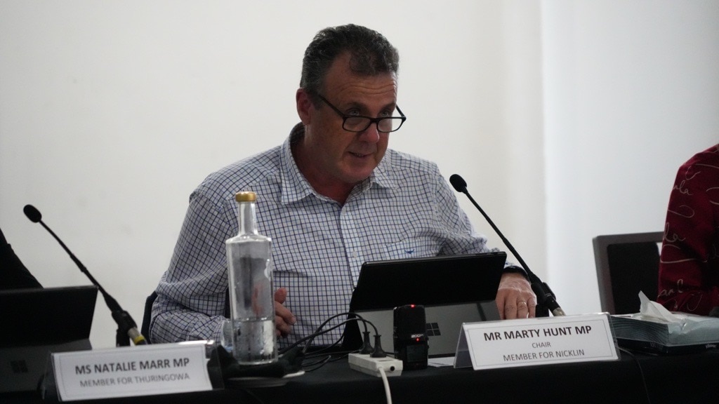 man in dress shirt sitting at table with laptop and microphone