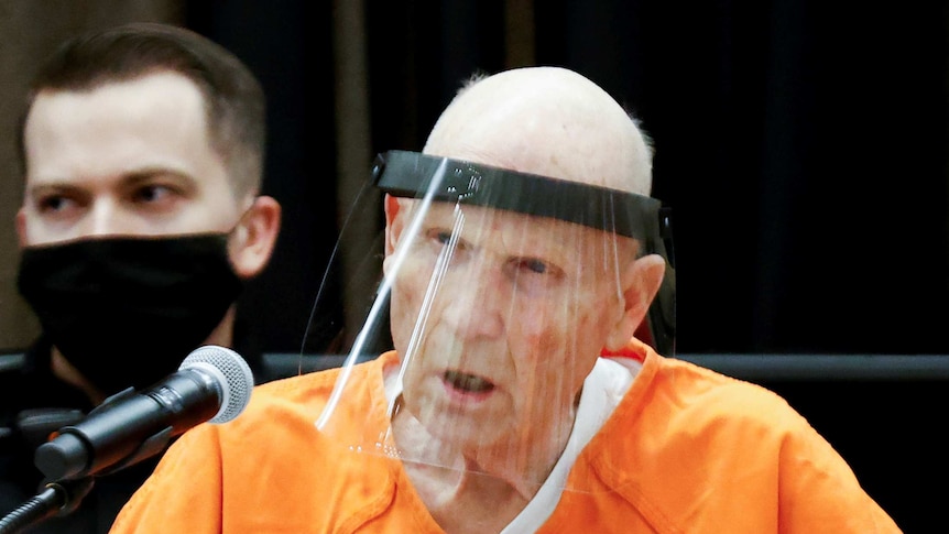 Former police officer Joseph James DeAngelo Jr wears a face mask and orange jumpsuit as he speaks in court.