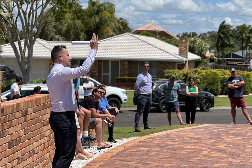 Auctioneer with people standing outside house