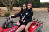 Christina and Irene Vithoulkas sit on a quad bike together on a gravel driveway of a rural property.