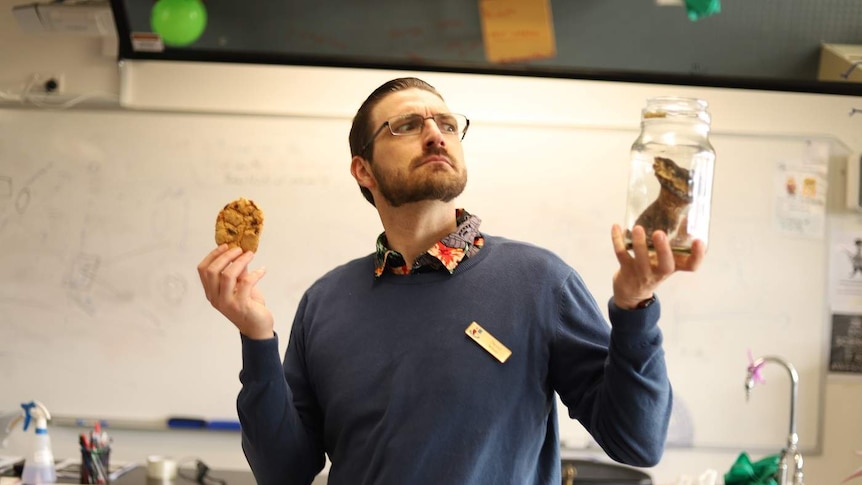 Daniel White holds a bug cookie and a jar with a specimen in it.