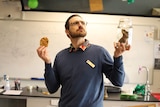 Daniel White holds a bug cookie and a jar with a specimen in it.
