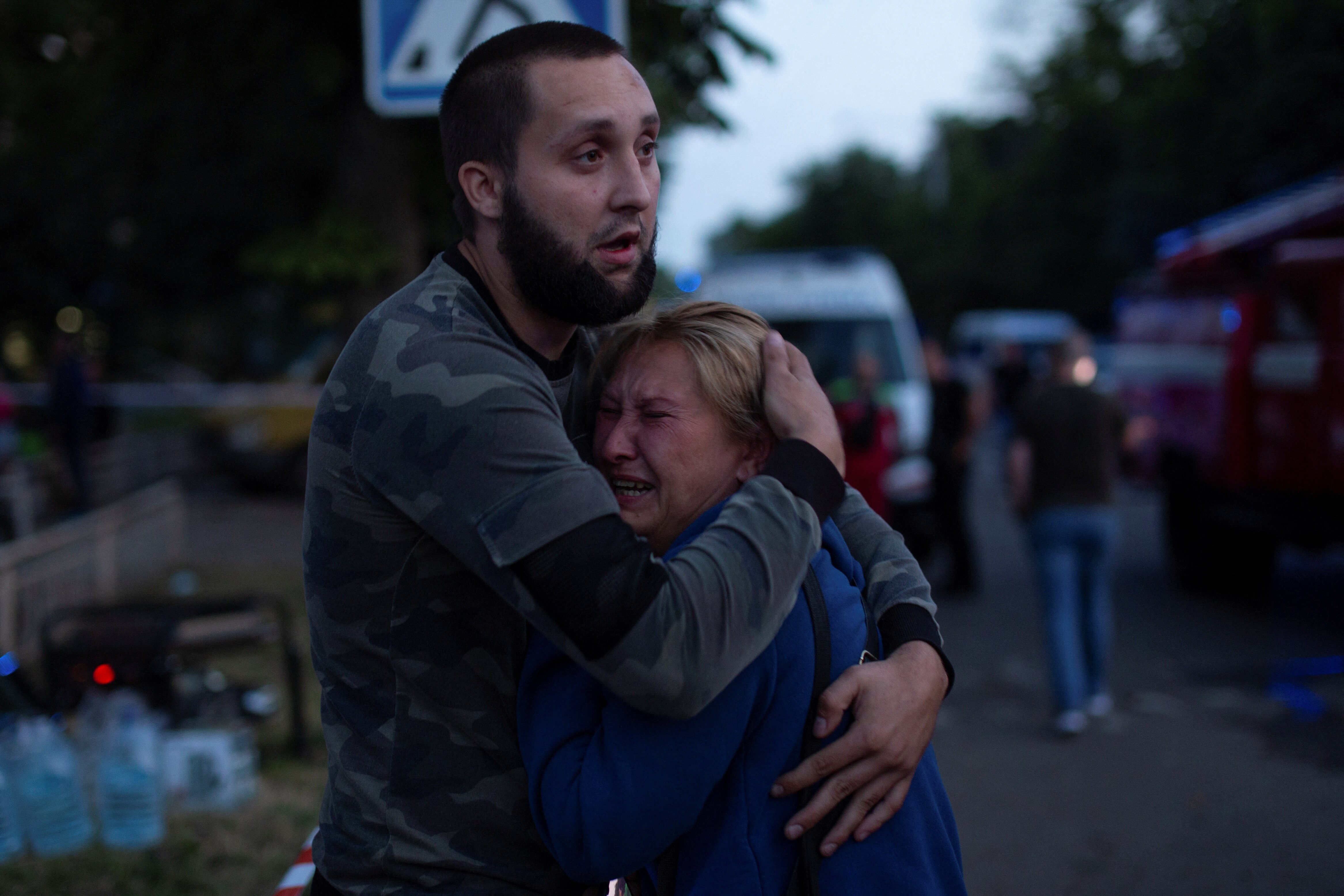 A man embraces a woman who is crying in fading light. 