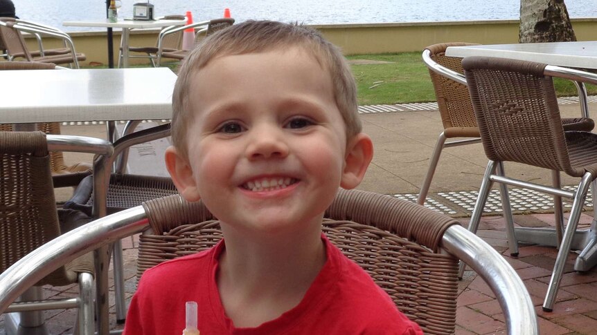 William Tyrrell in red shirt, sitting in chair with drink