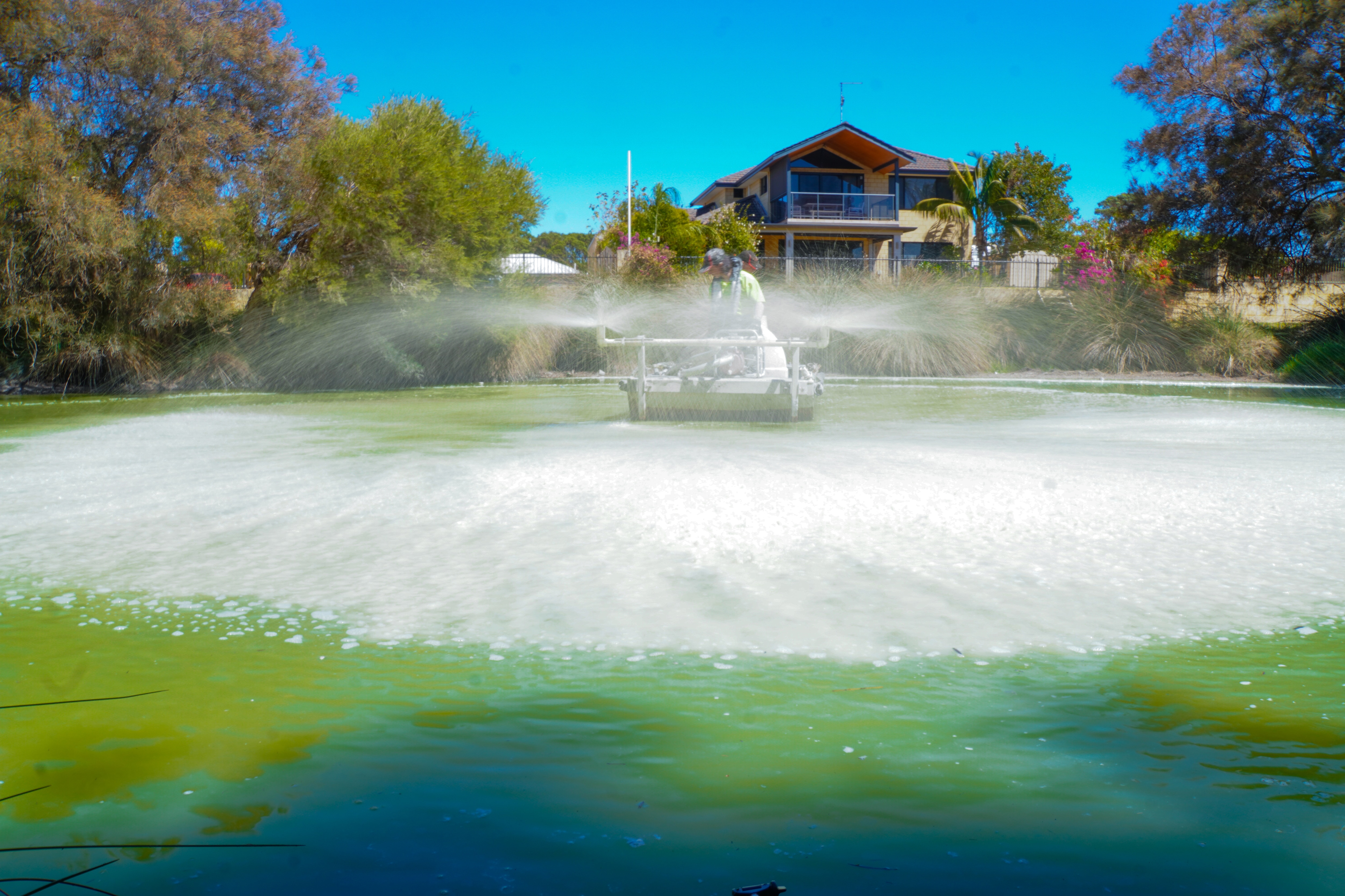 Boat on lake sprays liquid onto the surface