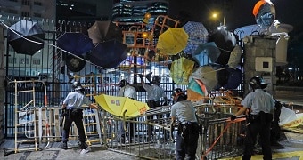 Riot police clear barricades and umbrellas blocked by protesters.