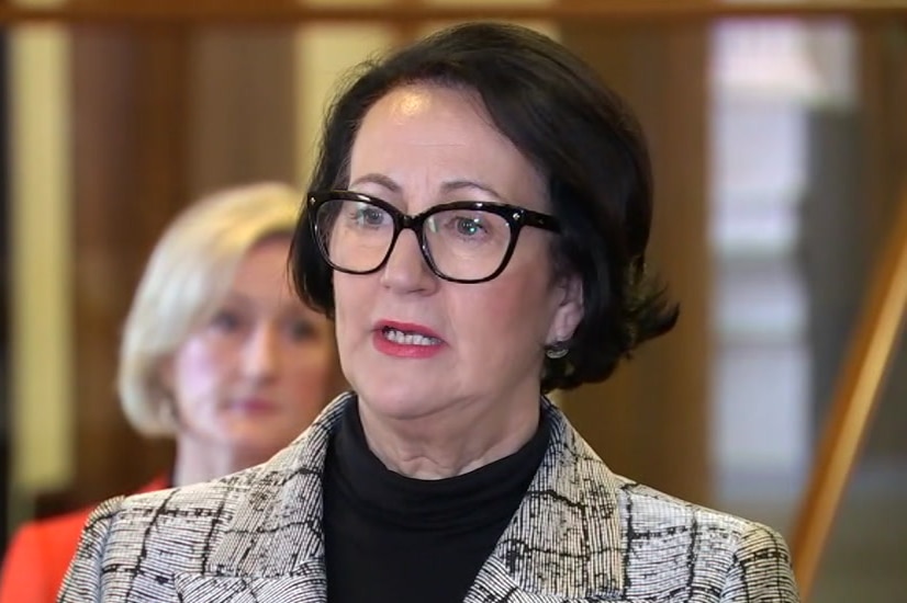 A woman with black hair and black glasses