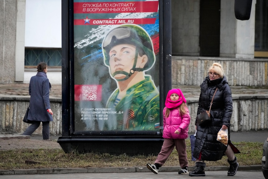 People walk past an army recruitment poster on a street in St Petersburg .