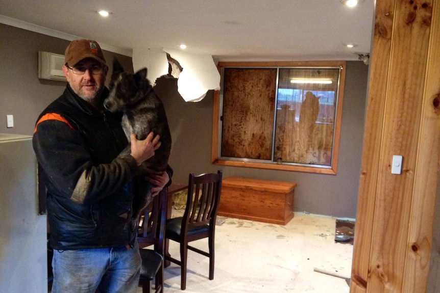 Sean Dicker shelters with his dog inside his East Ridgley home.