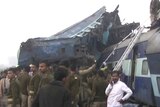 India's security forces personnel gather at the site of a train accident near Pukhrayan, a train is shown mangled and derailed