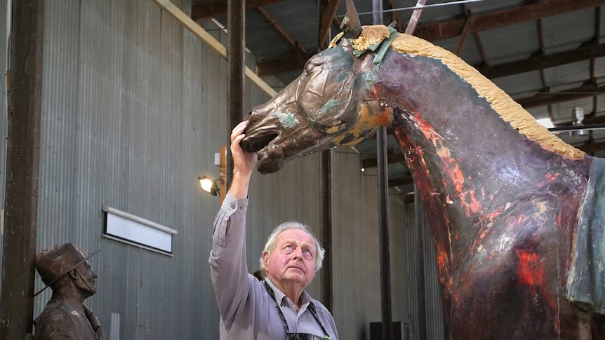 Sculptor Carl Valerius touching his statue of WW1 war horse Bill the Bastard