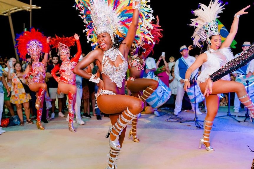 Dancers with feathered headpieces and sequined outfits.