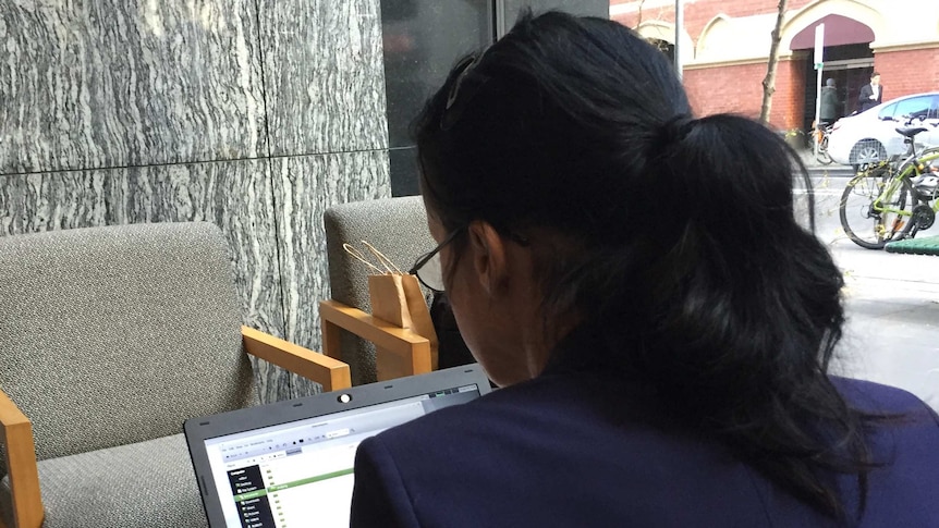 A woman sits at her laptop