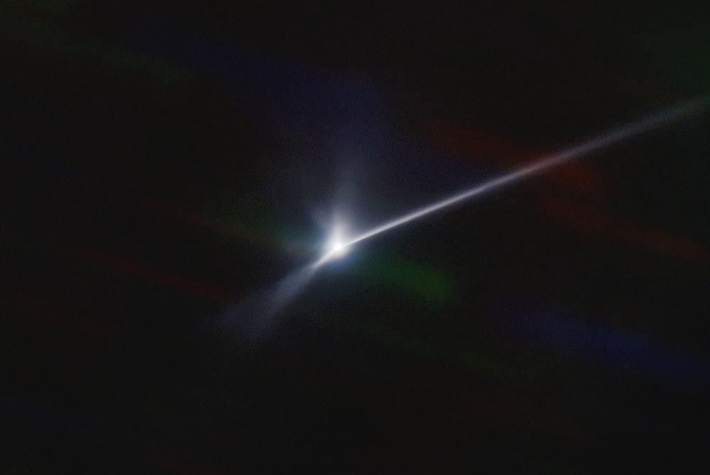 A long, bright white streak is seen on a pitch black background