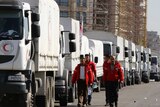 A Red Crescent convoy of aid trucks lined up on a Damascus street.