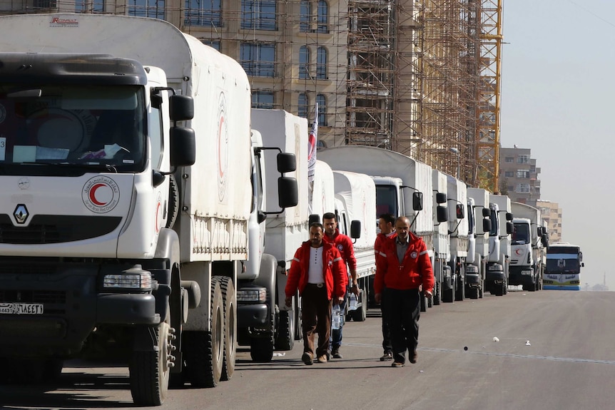 A Red Crescent convoy of aid trucks lined up on a Damascus street.