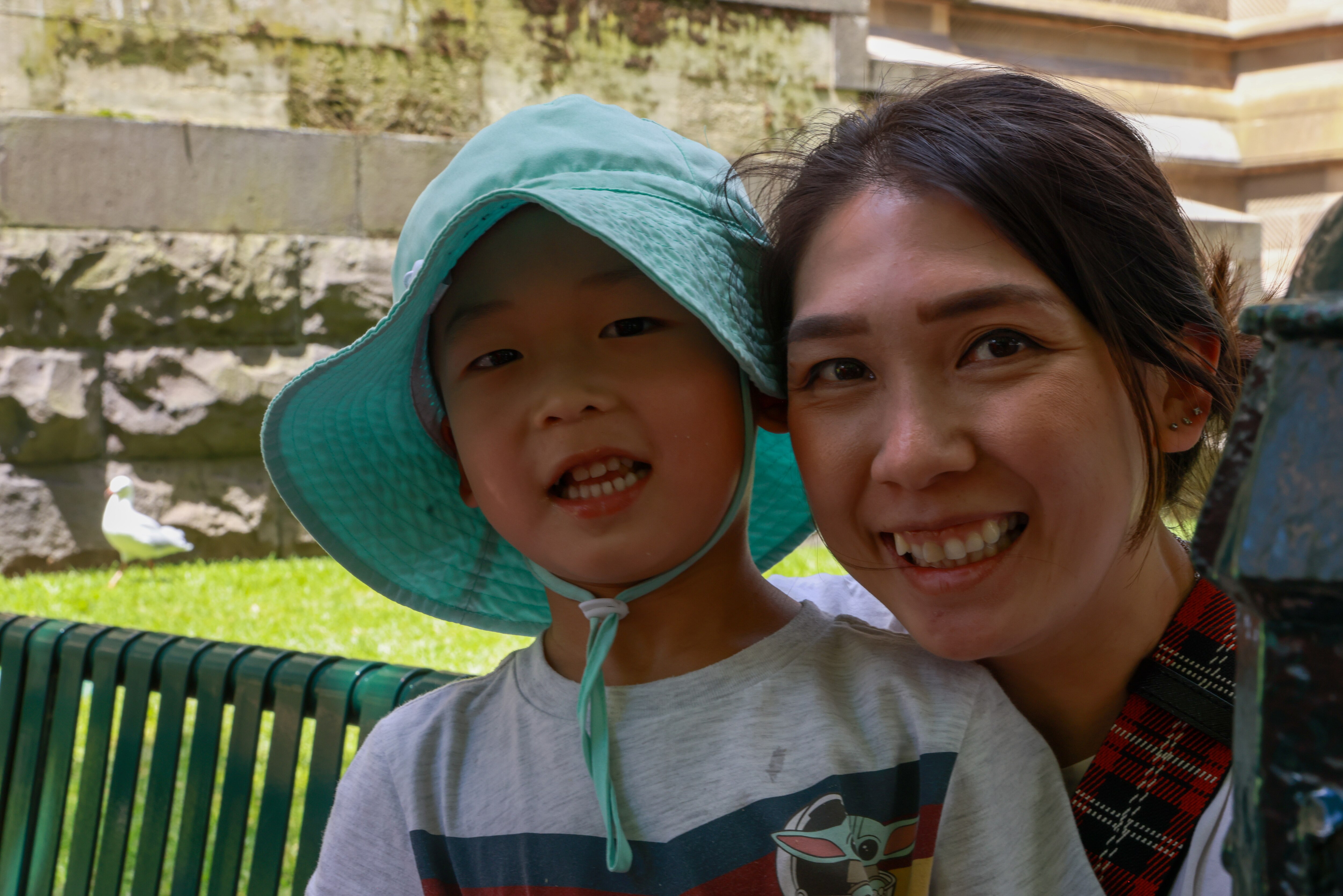 Faded social distance stickers on the footpath and people walking with masks as they pass hand sanitiser stations.