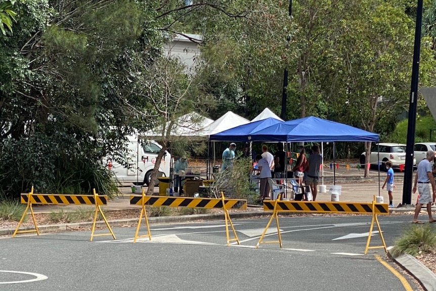 A marque in the distance in bushy environment with orange and black barricade in front of the marquee