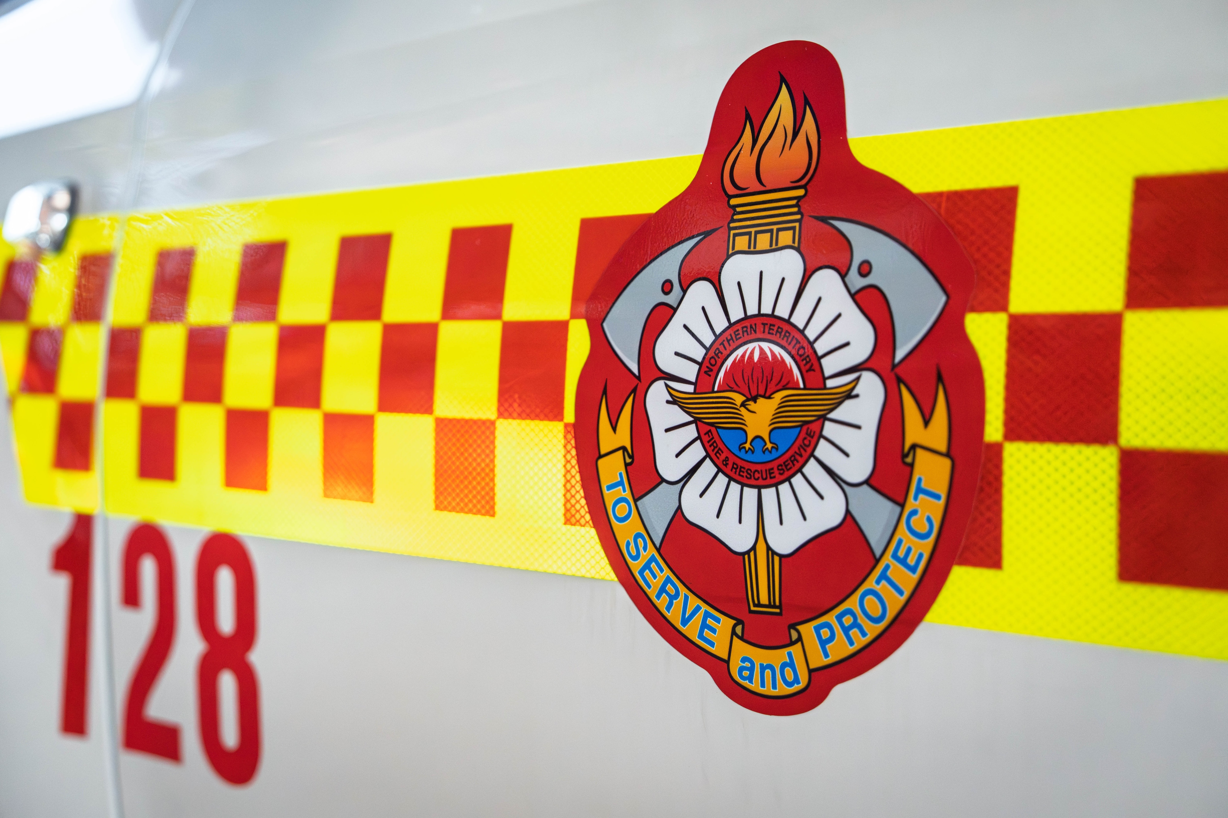 A close-up of a logo on the side of NT Fire and Rescue Service vehicle reads: to serve and protect.