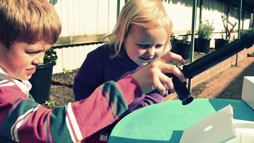 Benjamin Huckel uses a telescope and a piece of paper to show his sister, Tabitha, the transit of Venus.