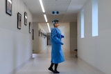 A nurse stands in PPE in a hospital corridor.