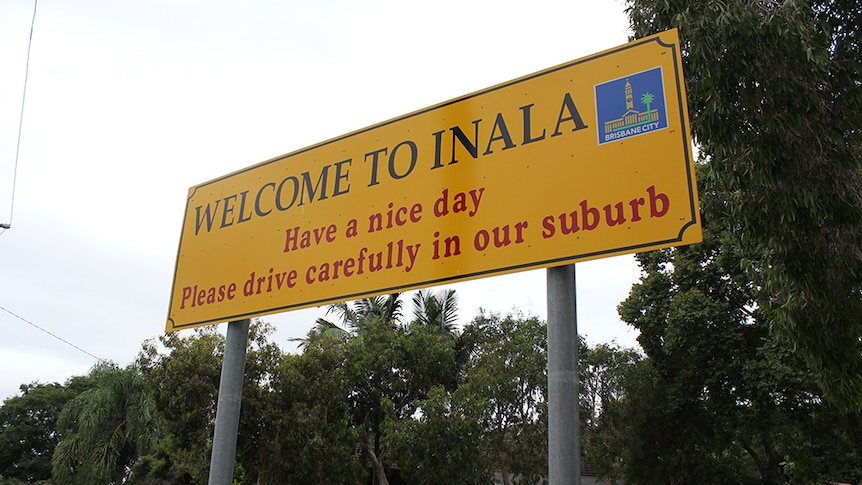 A yellow sign reading "Welcome to Inala, Have a nice day, Please drive carefully in our suburb".